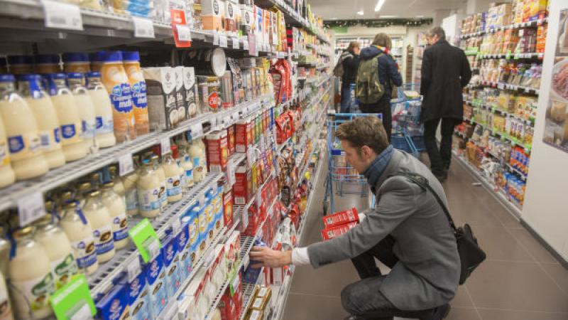 Klant pakt koffie uit een schap in de supermarkt